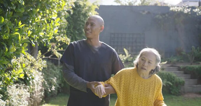 Senior woman and male aide spotting plants, woman pointing with wooden cane while aide supporting