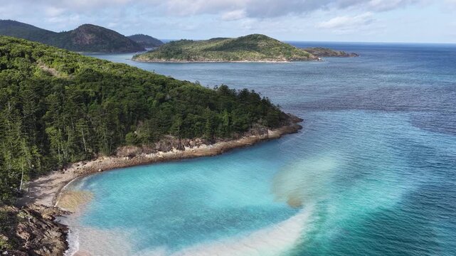 Aerial view of the turquoise waters with coral spawning and lush green hills of Whitehaven Beach in the Whitsunday Islands, Queensland, Australia.