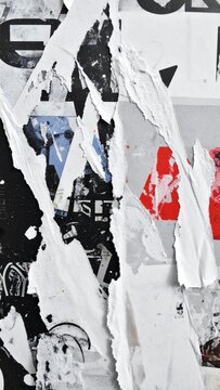 Macro texture of overlapping weathered wet street posters with heavily torn edges