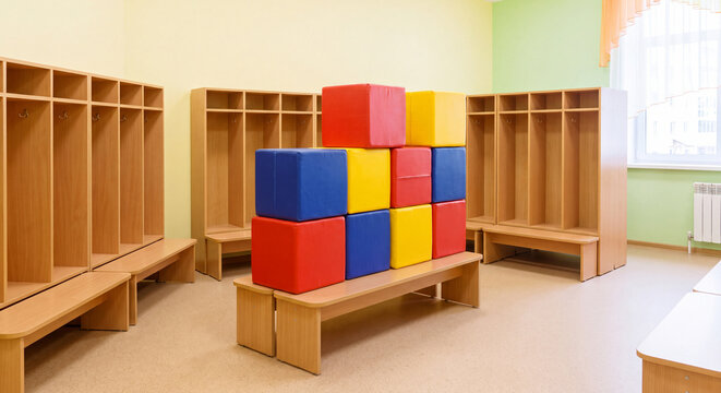 Spacious and clean kindergarten locker room featuring wooden storage cubbies coat racks and stacked colorful soft foam play blocks.