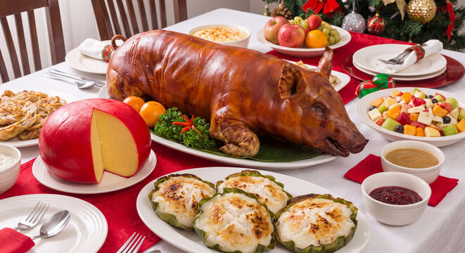 A luxurious holiday banquet table centered with a whole crispy roasted suckling pig surrounded by cheese fruits and savory baked appetizers