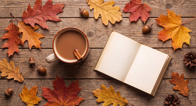 Flat lay of an open blank book beside cup of warm tea surrounded by colorful red and yellow fall leaves on dark wooden background