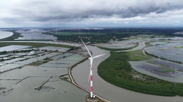 Aerial view of the Cox's Bazar 60 MW Wind Power Plant featuring a large wind turbine standing in a coastal wetland area near Cox's Bazar, Chittagong Division, Bangladesh.