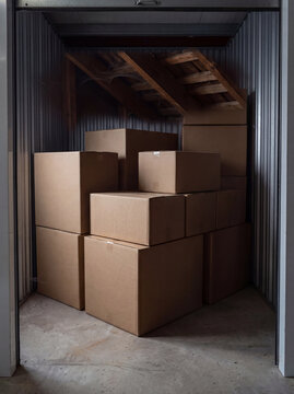 Multiple brown cardboard moving boxes are organized in vertical stacks within a metal self storage container unit