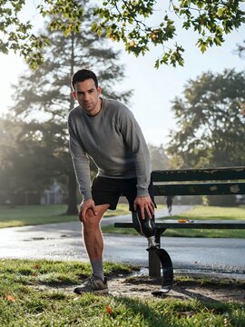 Man with prosthetic running blade stretching by a park bench &ndash; Ideal for adaptive sports campaigns, disability inclusion, or fitness content