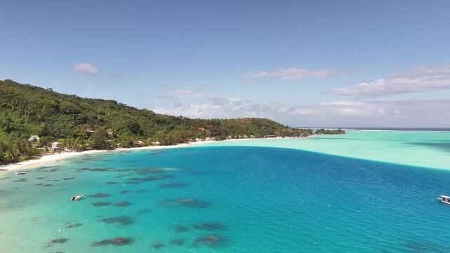 An aerial drone shot shifts left over the deep blue waters of Povai Bay, tracking along the sandbars, tropical coastline, and turquoise lagoon flats of Bora Bora