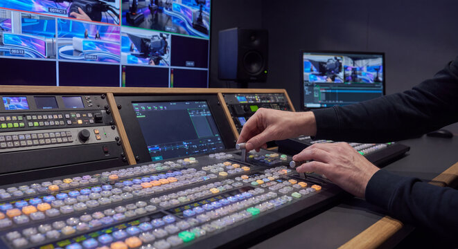 Close up perspective of operator hand pressing colorful backlit switcher buttons on professional television video mixing switcher console
