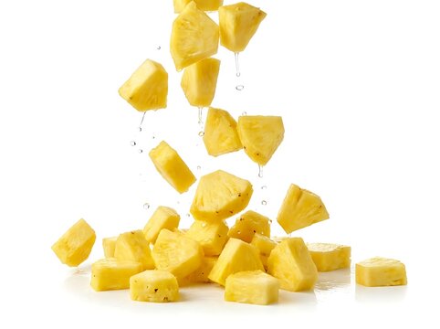 Fresh pineapple chunks falling on white background