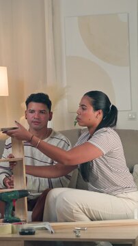 Close up shot of a cheerful young couple high fiving each other in celebration after successfully finishing flat pack wooden furniture assembly together in a cozy modern living room interior