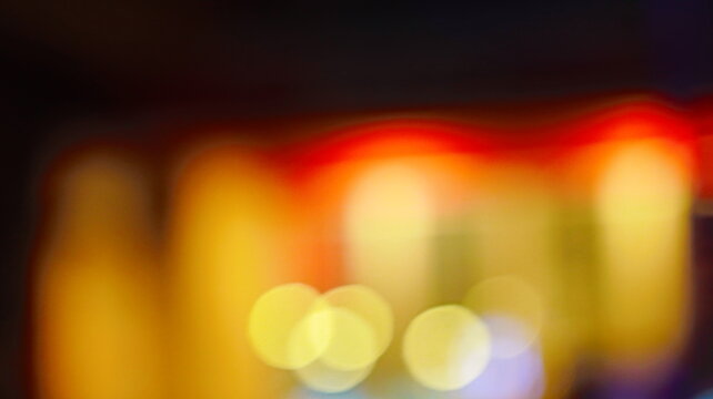 Abstract bokeh light background with glowing yellow and orange circles against a dark festive backdrop for creative design use