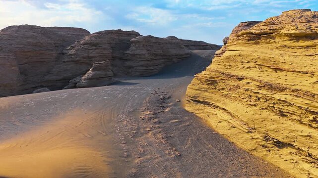 Sunlit wind-eroded sandstone canyon and layered rock formations in Dahaidao, Xinjiang, China, creating a dramatic desert travel and geology background.