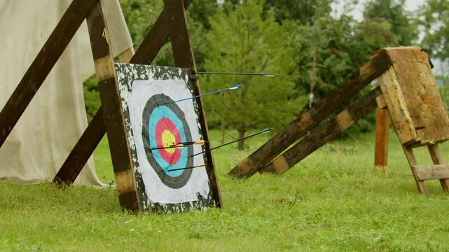 Caught mid flight, arrow drives into worn target among several earlier shots during rainy medieval event. authentic setting of traditional archery demonstration.