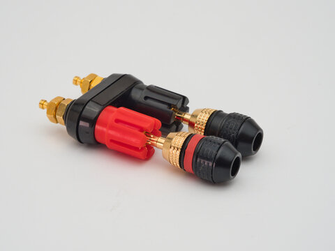Banana Plug Connectors - Pair of audio banana plug connectors with gold-plated tips on a binding post adapter, isolated on a clean white background.