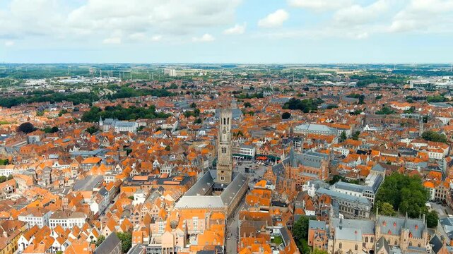 Bruges, Belgium. Belfort - Medieval bell tower and market square. Panorama of the city center from the air. Cloudy weather, summer day. Drone footage