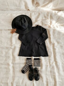 Child witch costume flat lay with hat and striped socks &ndash; Ideal for Halloween dress-up guides, kids fashion, or party planning