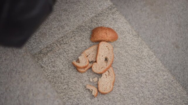 Close up of bread slices arranged on gray stone surface with soft lighting and minimal camera movement. scene features several pieces of sliced brown loaf including crumbs scattered