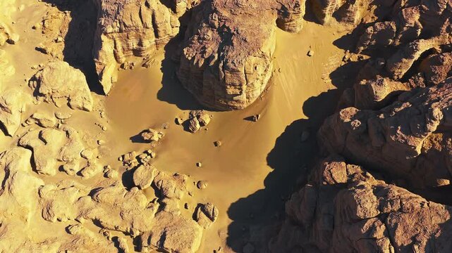 Top-down aerial view of eroded sandstone formations and windblown sand in a remote desert landscape, ideal for geology, travel, and natural texture concepts.