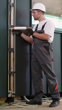 Professional construction worker applying silicone sealant with a caulking gun