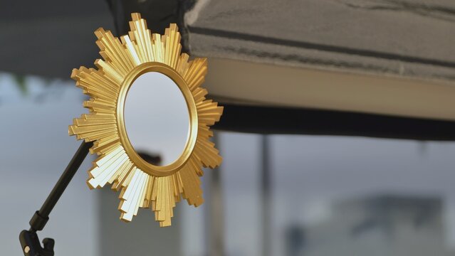 Golden sunburst mirror reflecting room details and studio equipment