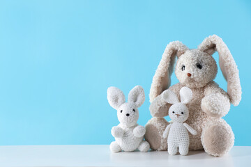 Fototapeta premium Cute stuffed toys on white table against light blue background. Space for text