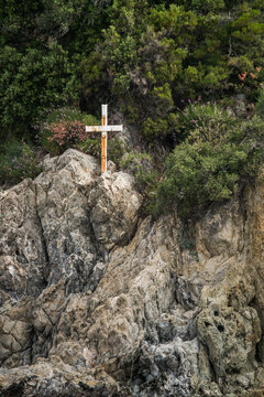 A metal cross on the rock near The Arsanas Gregoriou monastery (port building) of Monaster, on Mount Athos, seen from the sea, Greece. June 4, 2026