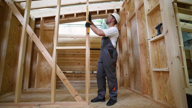 Construction worker using spirit level on wooden frame