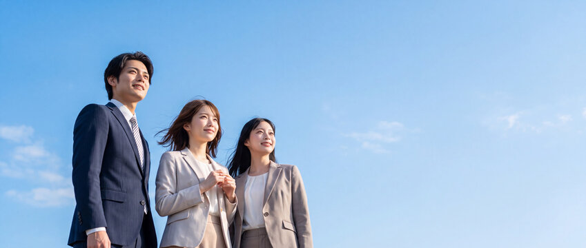 澄み渡る青空のもと未来を見据えるスーツ姿の若いビジネスパーソン（就職活動・新卒・挑戦・希望）