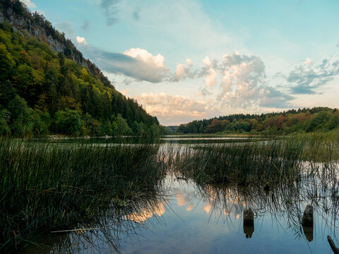 Paysage naturel du lac du Petit Maclu au Frasnois dans le Jura, entour&eacute; de for&ecirc;t, de falaises et de roseaux sous un ciel nuageux