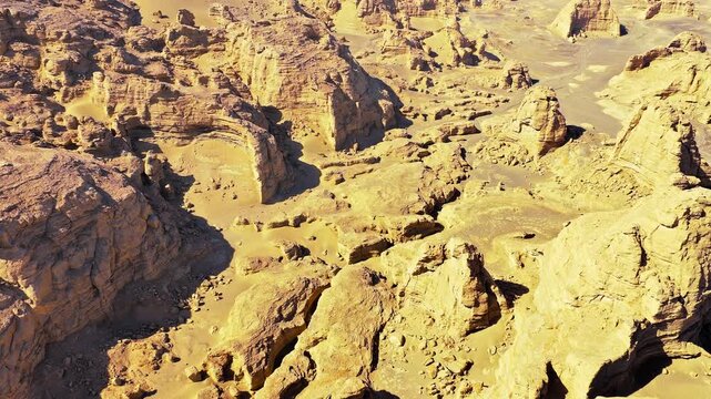 Sunlit aerial view of eroded sandstone yardangs and dramatic desert landforms in Dahaidao, Xinjiang, China.