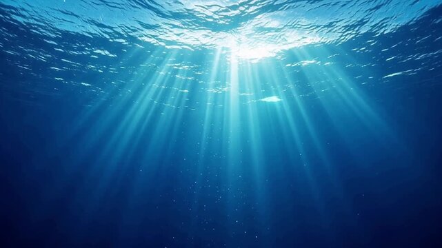 Sunlight breaking through blue sea water surface into deep ocean with underwater light rays