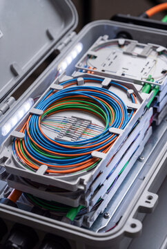 Open fiber optic splice closure with colorful fibers arranged in splice trays