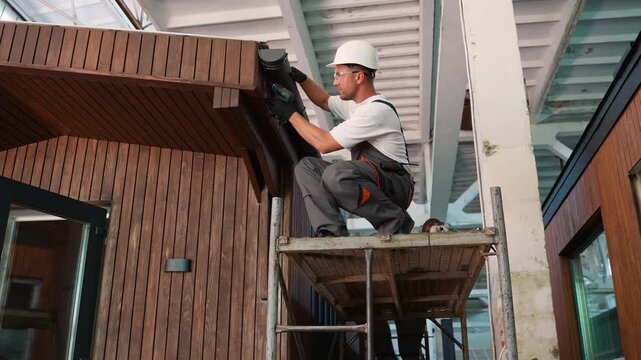 Construction worker installing gutter system on a wooden house