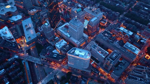 Lively dense city scenery with numerous city lights on in the evening. Drone footage over the modern cityscape of Boston, Massachusetts at dusk time.