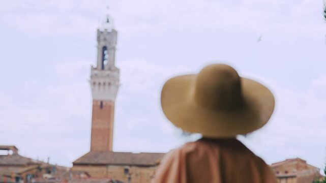 Tourist woman wearing hat enjoying beautiful Siena, Tuscany panoramic scenery