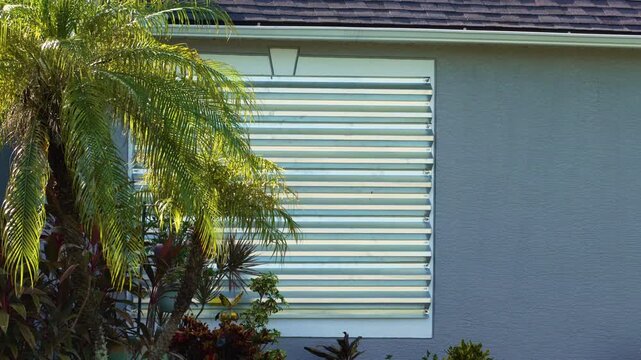 Hurricane shutters made from steel mounted for protection of house windows. Protective measures before natural disaster in Florida