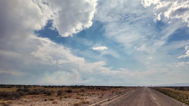 Driving down the Pony Express as smoke rises from a wildfire at the Tom Creek fire in the Utah desert.