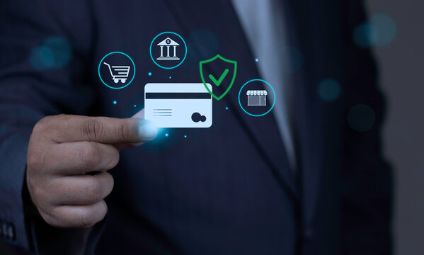 Secure credit card online payment and e-wallet transaction concept featuring businessman holding digital credit card with security shield and retail icons on dark background.