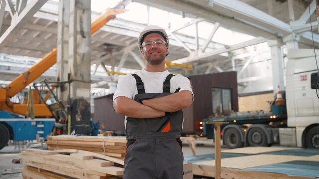 Confident construction worker standing with arms crossed in a factory