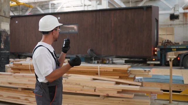 Foreman coordinating modular home transport with a walkie talkie