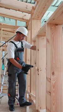 Professional carpenter assembling a wooden house frame structure