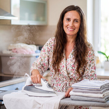 Young beautiful housewife ironing clothes at home