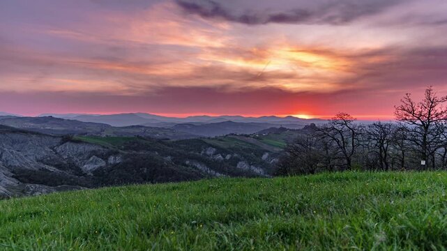 Camera slider time lapse of dramatic sunset clouds moving over rolling green hills in Canossa, Bolognese hills. Scenic countryside landscape in Emilia-Romagna, Italy.