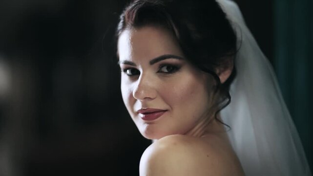 Elegant bride woman with veil gazing confidently and smiling towards the camera, cinematic isolated shot