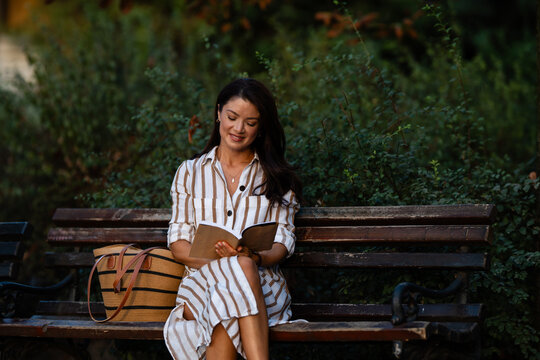 Woman reading book relaxing on park bench