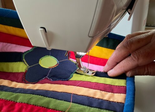 close up of a sewing machine and sewing a colorful patchwork quilt