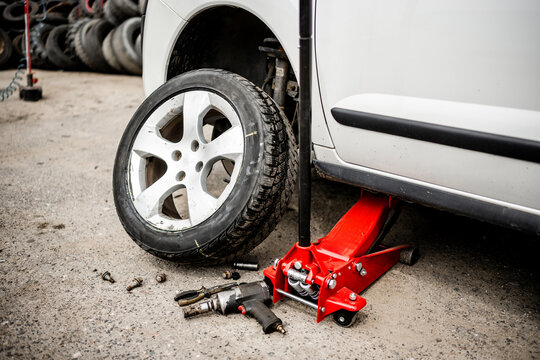 Mechanic changing a car tire at a workshop during daytime