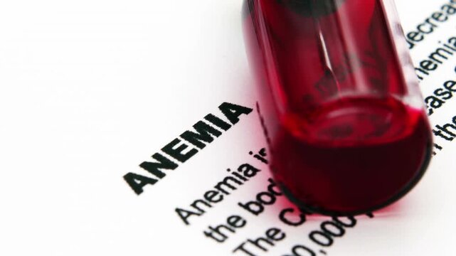 Close-Up of Blood Vial on Medical Document About Anemia and Diagnostic Test Results