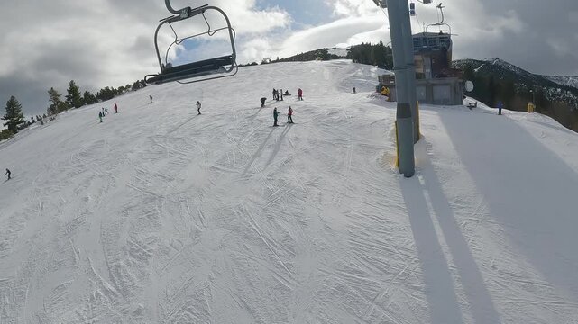 Skier pov from ski lift arriving on mountain summit station with people enjoying the snowy slopes at a winter resort in Borovets, Bulgaria
