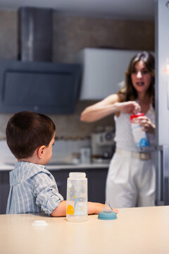 Mother preparing milk for child in kitchen