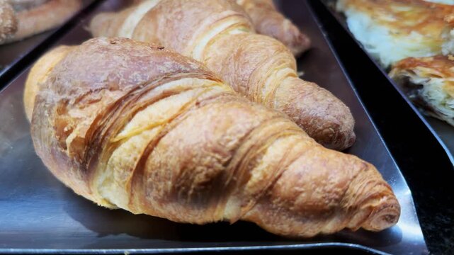 Close-up of fresh golden croissants displayed in a bakery shop window